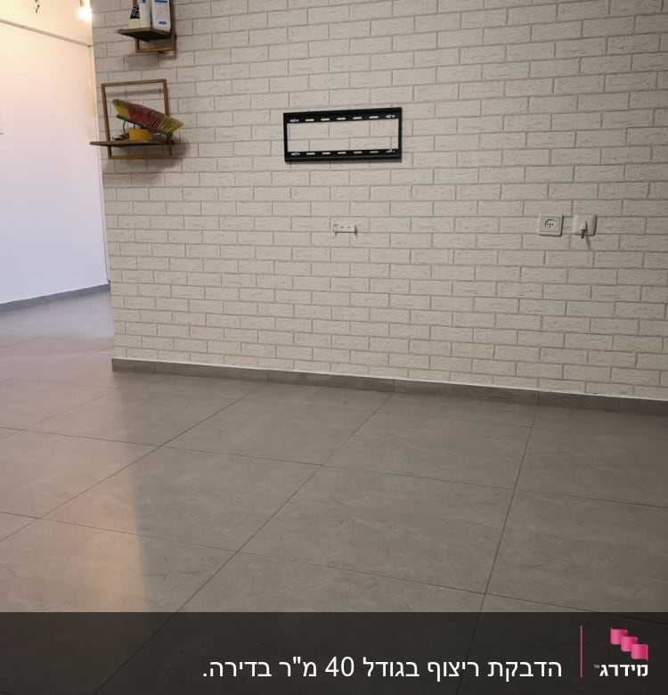 קיר לבנים עם מתקן לטלוויזיה, רצפת אריחים אפורה